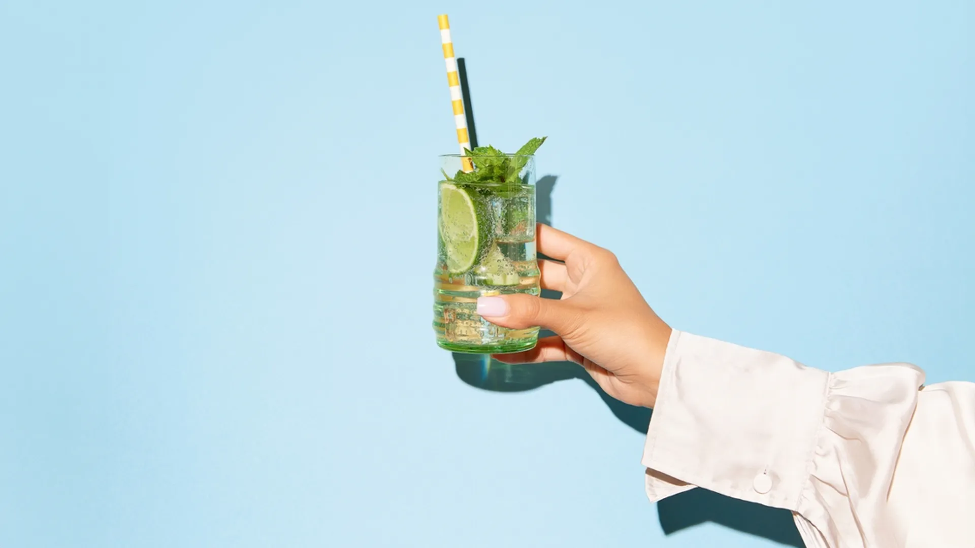 Food-Fotografie Trends 2025: Auffällige Farbexplosion mit einem erfrischenden Drink, Limette und Minze, inszeniert von Socialfood vor einem neonblauen Hintergrund.