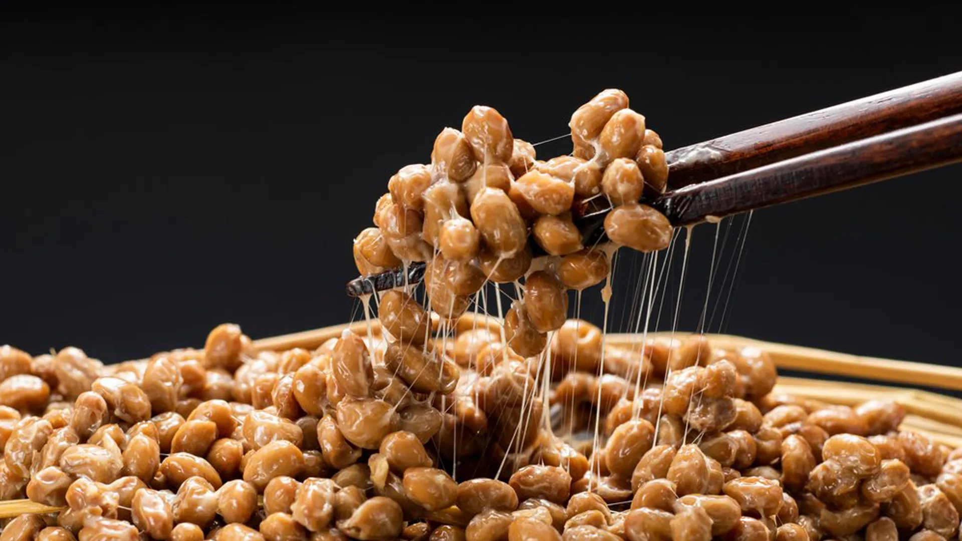 Hyperrealistische Food-Fotografie Trends 2025: Nahaufnahme von klebrigen fermentierten Bohnen, die feine Fäden ziehen, inszeniert von Socialfood für makellose Textur-Details.