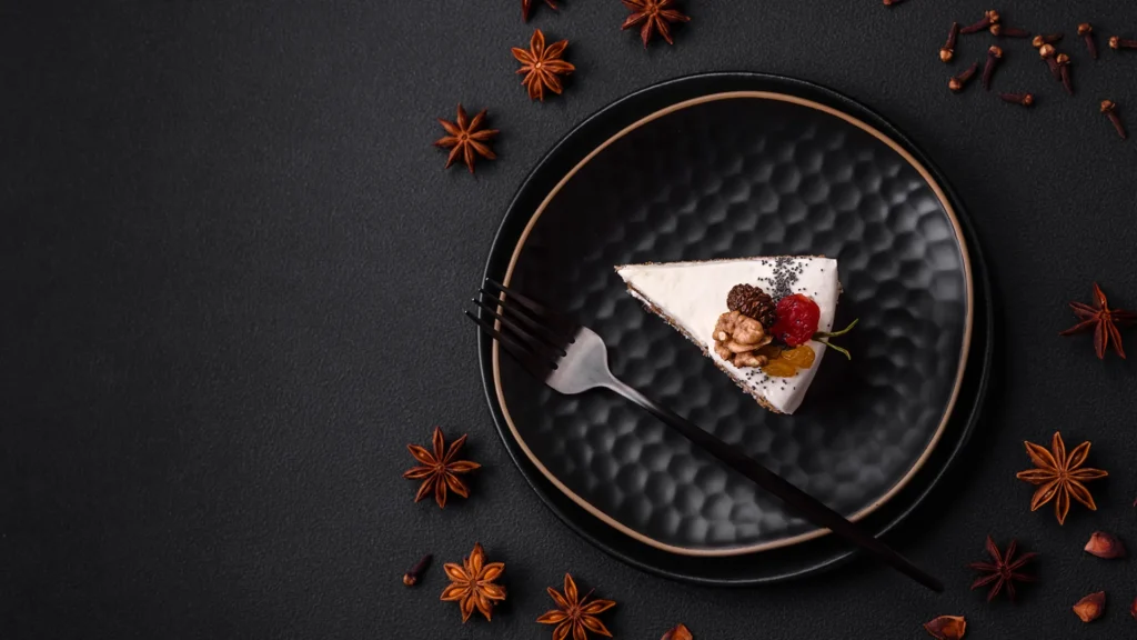 Stilvolle Food-Fotografie eines Kuchenstücks auf schwarzem Teller mit Sternanis und Gewürzen – perfekt inszeniert für modernes Marketing.